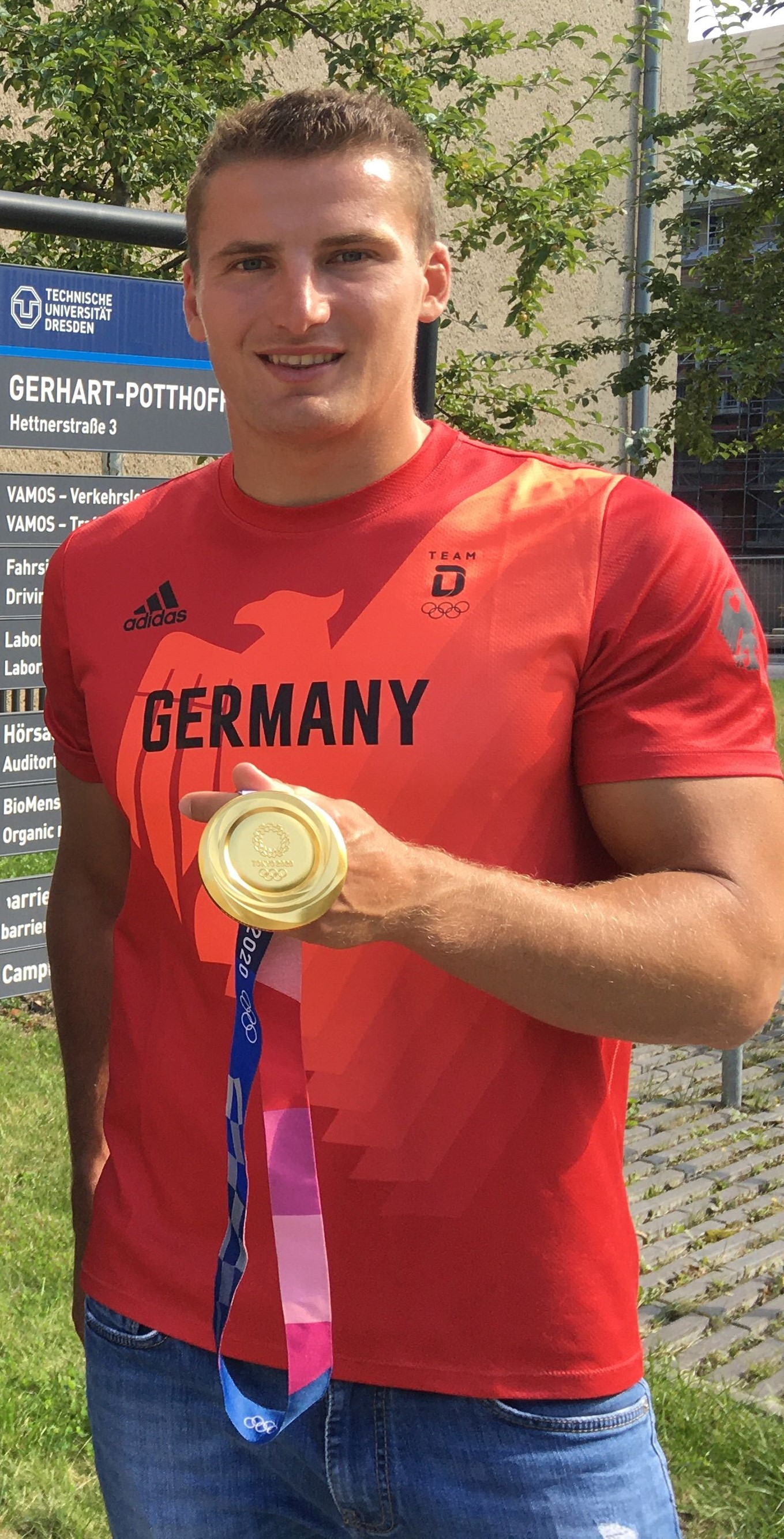 A young athletic man holding an olympic gold medal