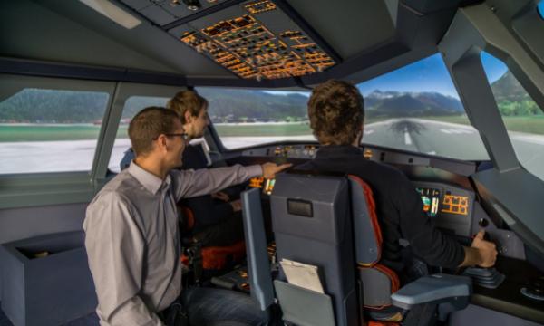 Three men sitting in a flight simulator.