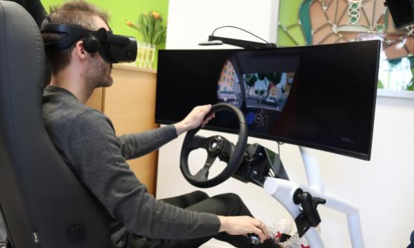 1 Person sitzt mit einer VR-Brille in einem Fahrsimulator