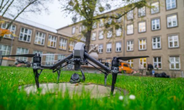 In the foreground is a drone on the lawn, behind it a building.