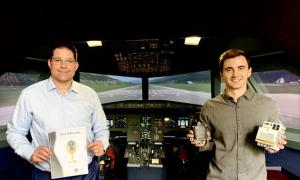  Two men stand in an aircraft cockpit. One of them holds a certificate in his hands.