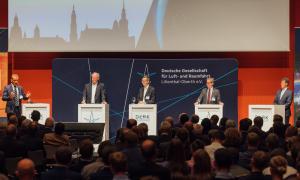 Panel discussion with 5 men in front of a large audience.