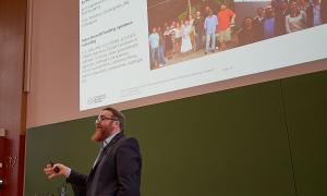 A man gives a lecture in a lecture hall in front of a blackboard