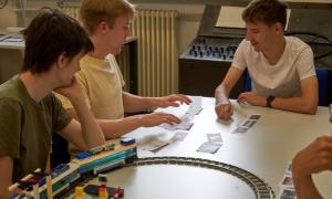 Three students sort cards on a table