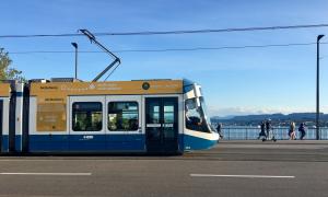 A blue and white tram is crossing a bridge in Zurich.