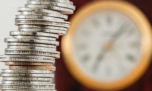 A tower of money coins and a clock in the background