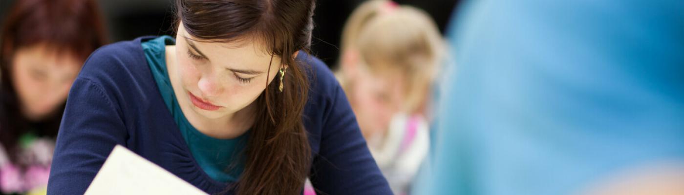 The photo shows concentrated students writing an exam.