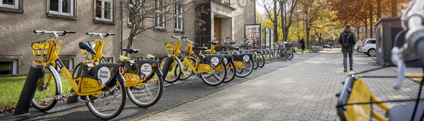 Gerhart-Potthoff-Bau der TU Dresden - Sitz der Fakultät Verkehrswissenschaften Außensicht auf ein TUD-Gebäude mit gelben Leihrädern davor.
