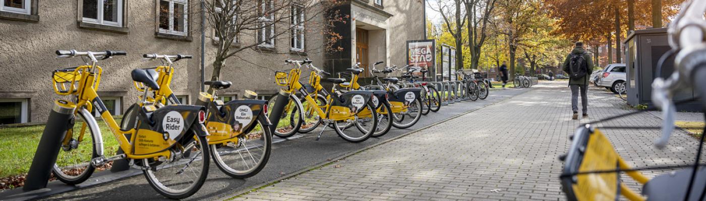 Außensicht auf ein TUD-Gebäude mit gelben Leihrädern davor.