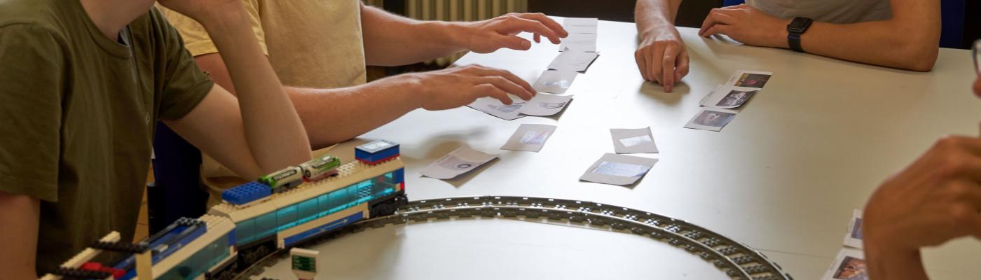 Three students sort cards on a table