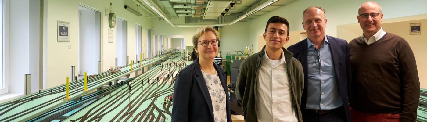 Eine Frau, ein Student und zwei Männer stehen im Eisenbahnlabor der TU Dresden