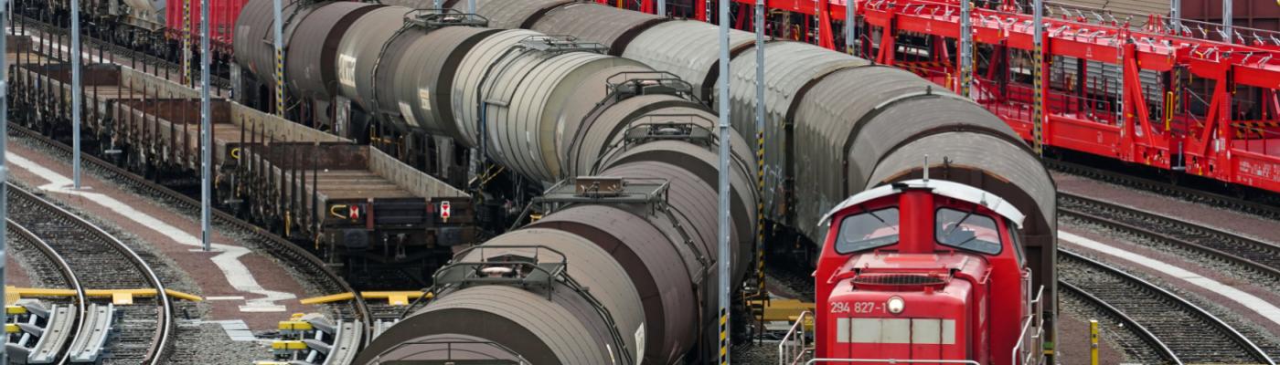 Ein Rangierbahnhof mit vielen Zügen mit Waggons. Eine Lok zieht einen Zug.