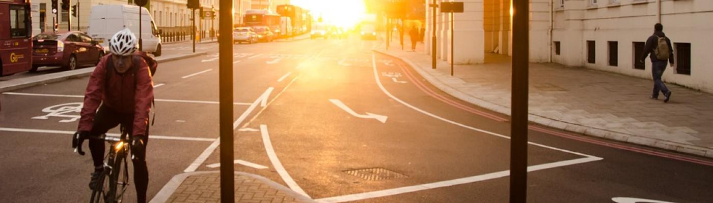 Fahrradfahrer mit Helm auf Straße vor Sonnenaufgang