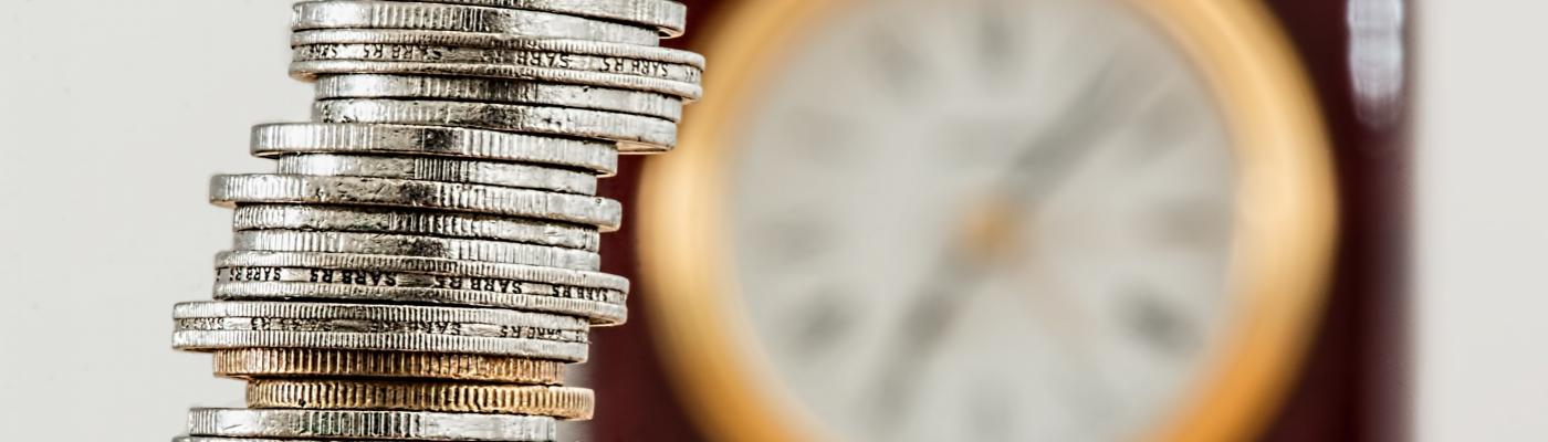 A tower of money coins and a clock in the background