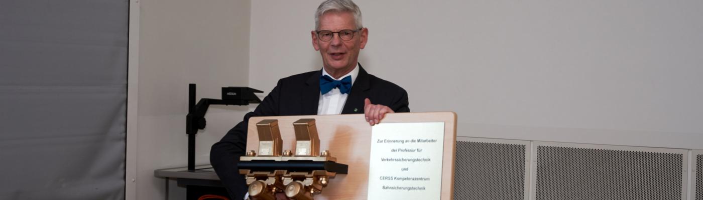 Older man with bow tie holds a gift