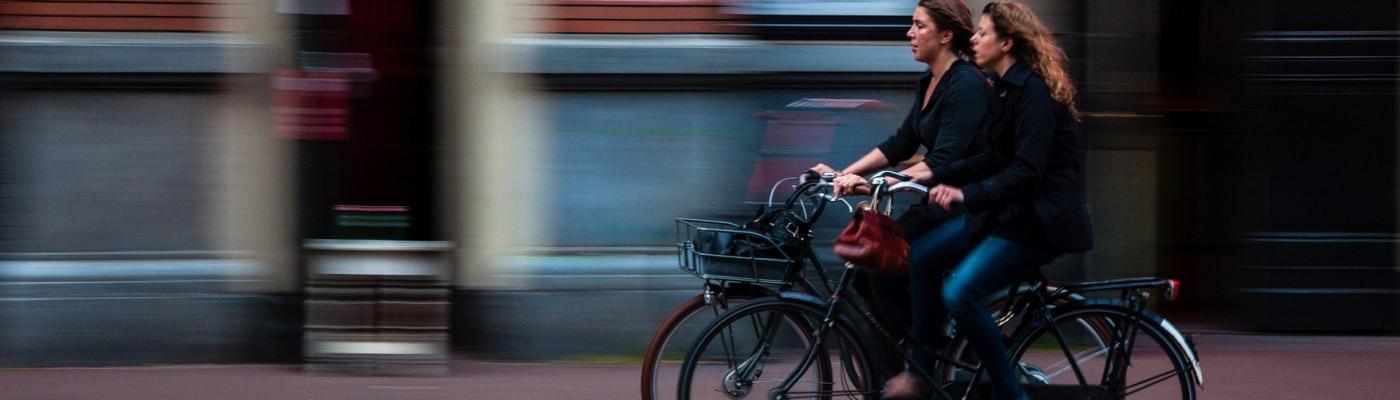 Zwei Frau auf Fahrrädern rollen durch die Stadt